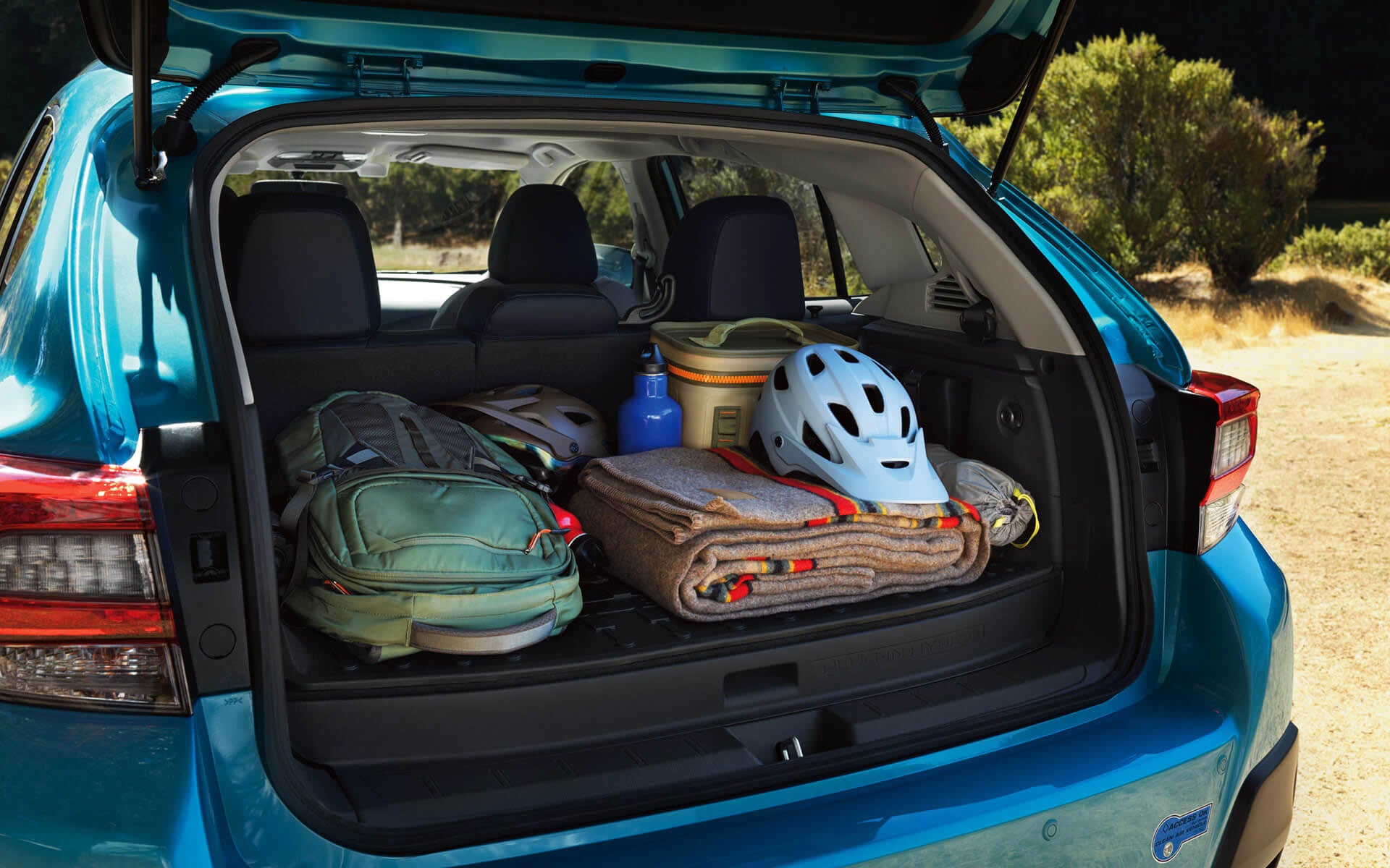 A backpack, blanket, and bike helmet in the rear cargo area of a Crosstrek Hybrid | Five Star Subaru in Grapevine TX